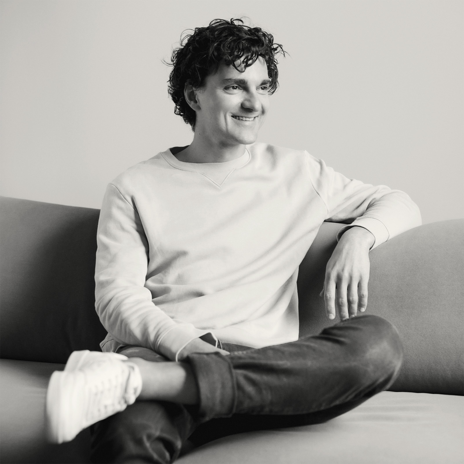 Picture of Patryk Kabaj sitting on a sofa, smiling and looking left.